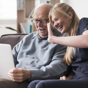 Image of an old man and a young woman looking at a computer.