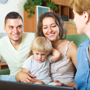 Image of two parents sitting with their child and talking to someone.