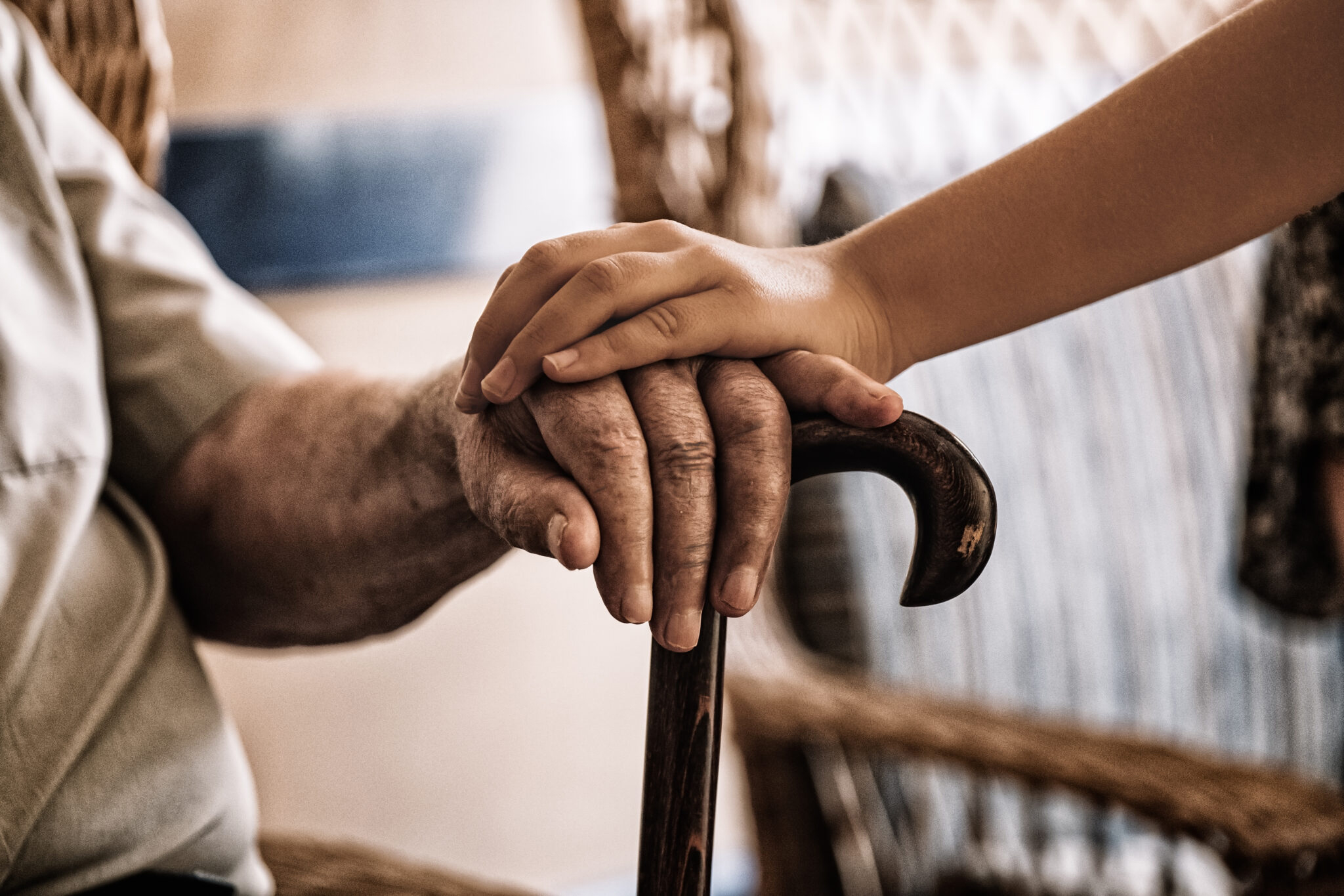 Image of a child's hand over an old man's hand holding a cane for Jewish Healing Services.